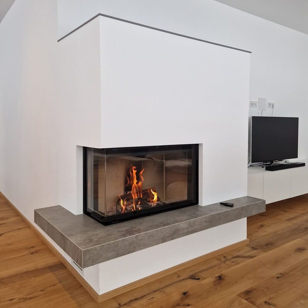 Moderner Kachelofen perfekt integriert in einer weißen Wand, der Boden ist aus Holz