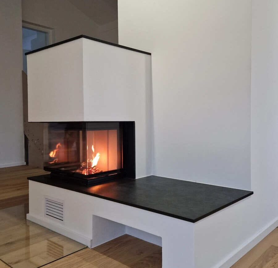 Moderner Kachelofen perfekt integriert in einer weißen Wand, der Boden ist aus Holz