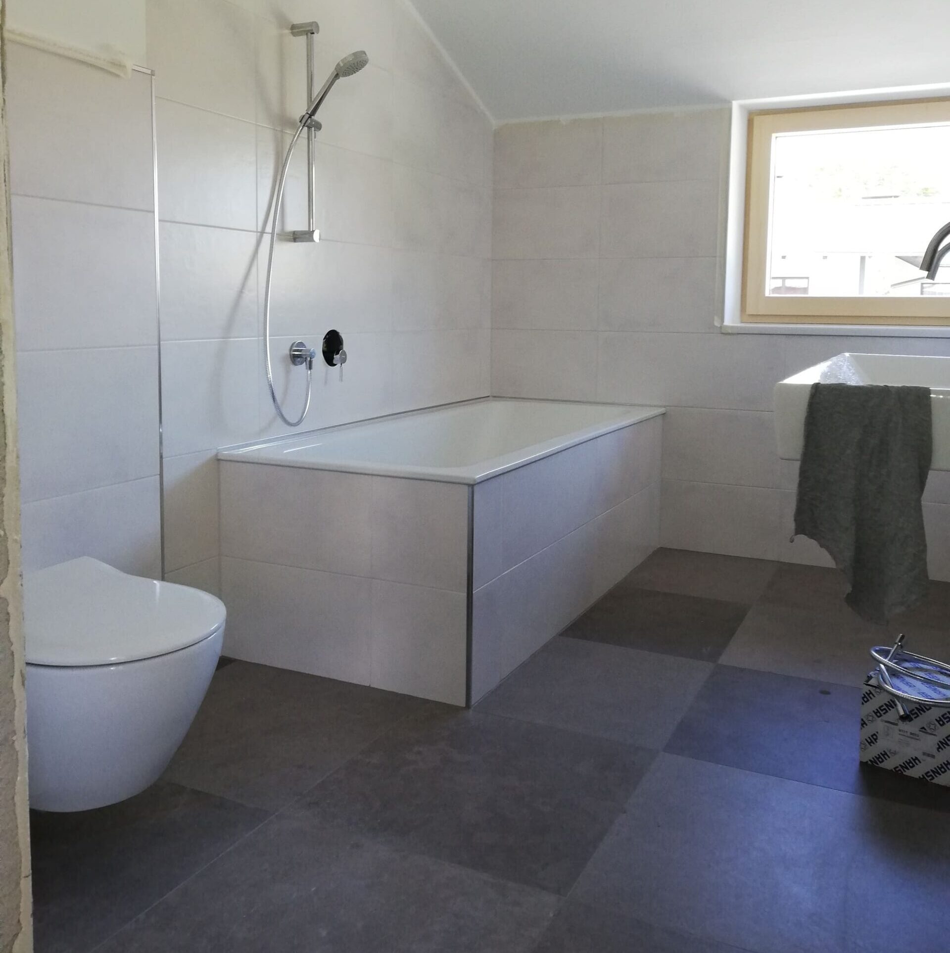 Modernes Bad mit weißer Toilette und moderner gefliesten Badewanne