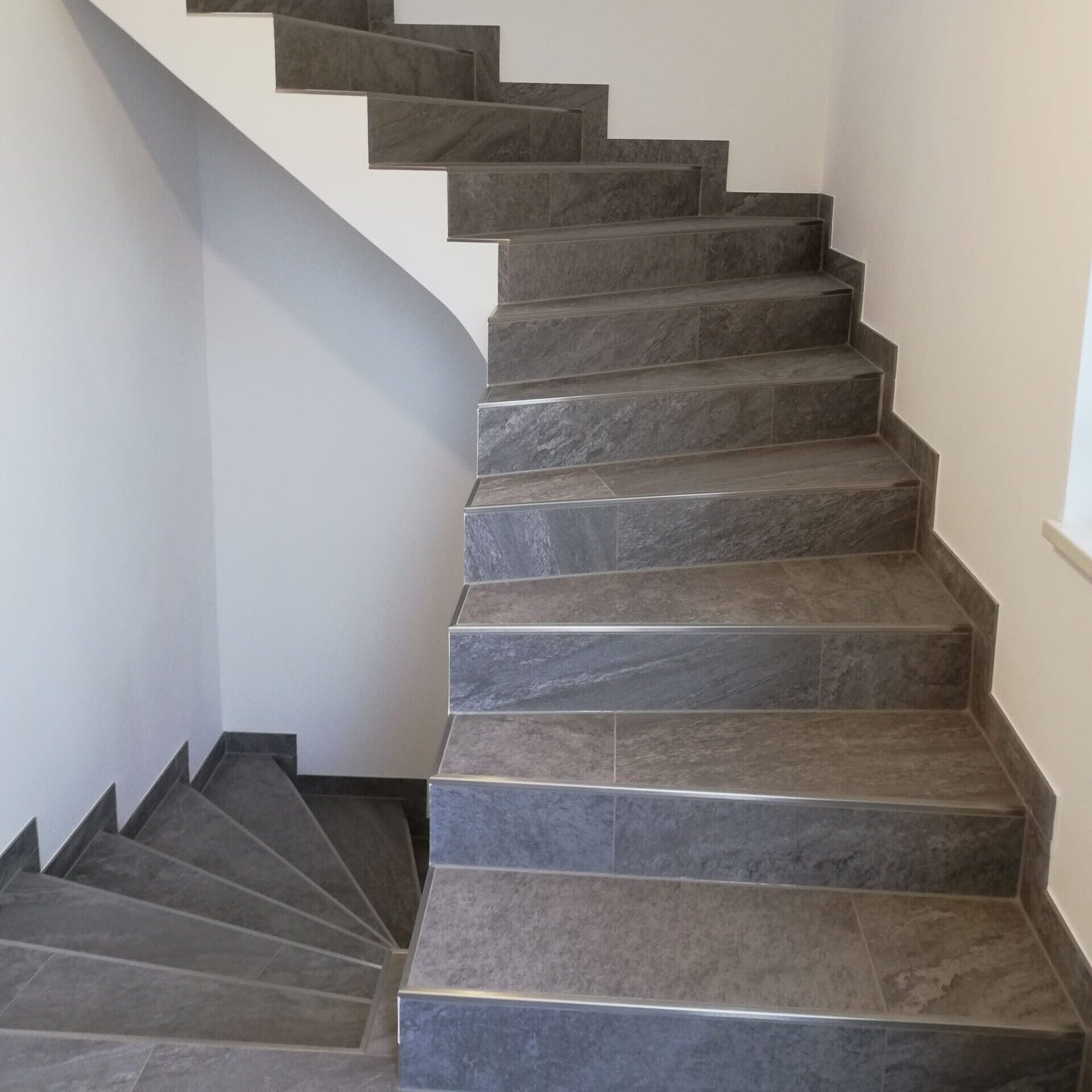 Frisch gefliestes Stiegenhaus mit weißer Wand