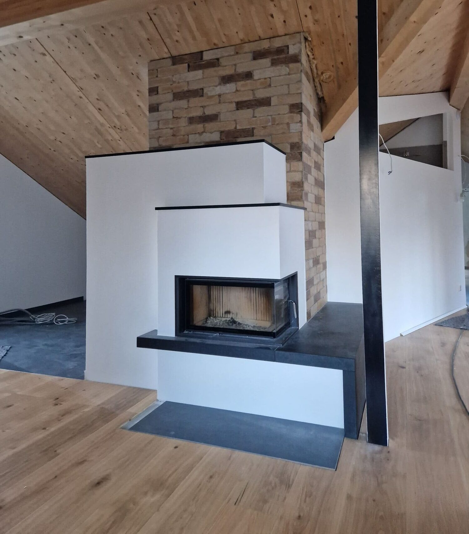 Moderner Kachelofen perfekt integriert in einer weißen Wand, die Decke des Raumes ist aus Holz