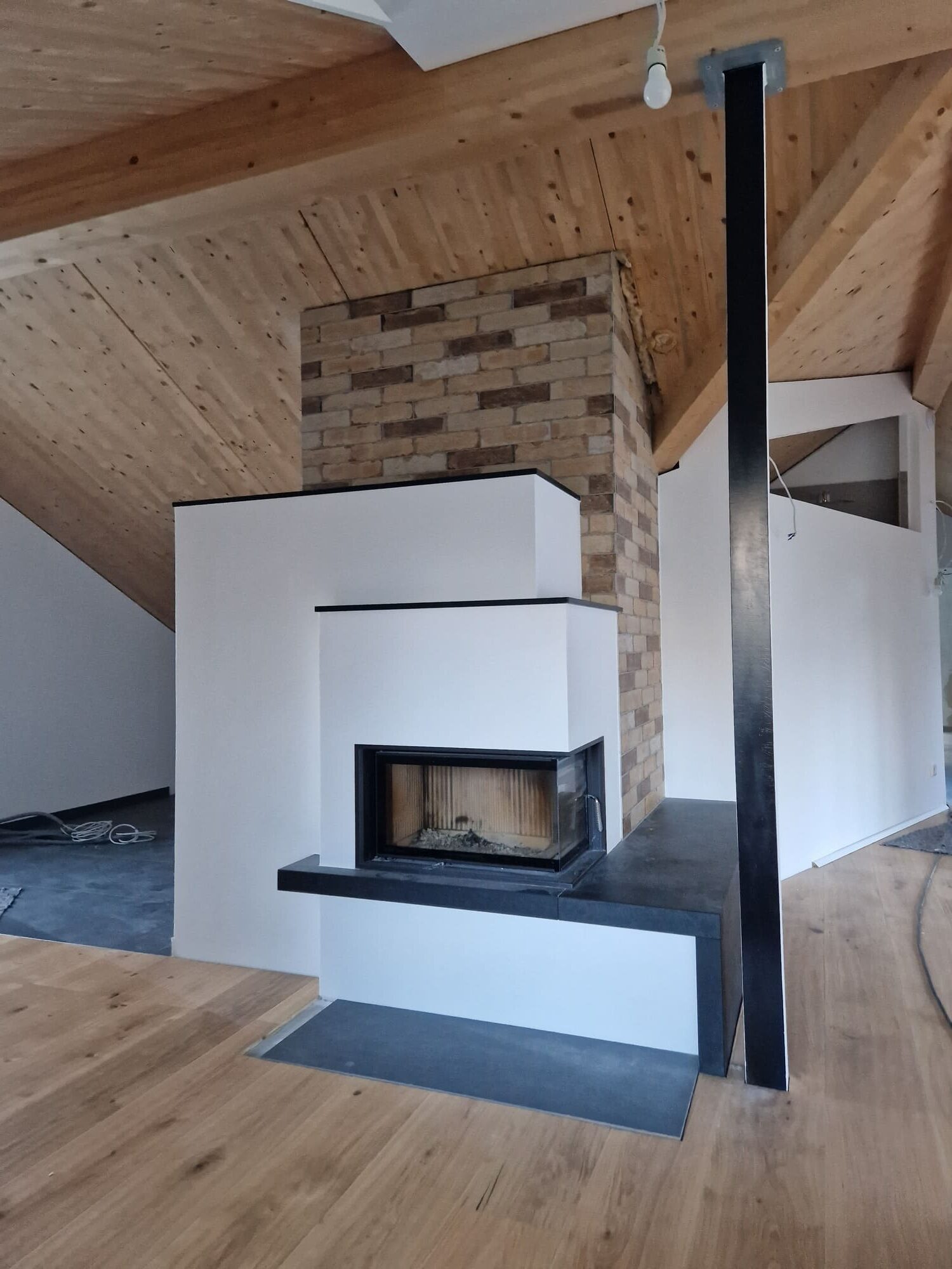 Moderner Kachelofen perfekt integriert in einer weißen Wand, die Decke des Raumes ist aus Holz